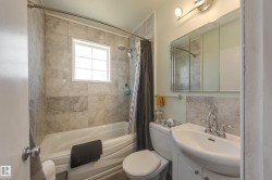 Bathroom featuring a tiled shower surround, built-in bathtub, window with grid pattern, wall-mounted vanity sink, and mirrored medicine cabinet - 