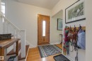 Entryway featuring a paneled wood-finish door with decorative glass insert, wood-finish flooring, white painted staircase with wood-finish treads, and an arched doorway opening to an interior room - 11516 72 Avenue, Edmonton, AB  - Indoor Photo Showing Other Room 