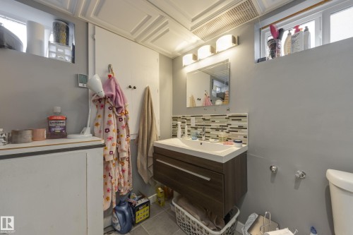 Modern bathroom featuring a floating wood-finish vanity with an integrated sink, a rectangular mirror, and an illuminated three-light fixture - 11516 72 Avenue, Edmonton, AB - Indoor Photo Showing Other Room