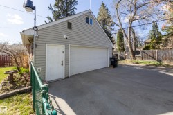 Detached two-car garage with light gray siding and a white paneled door - 