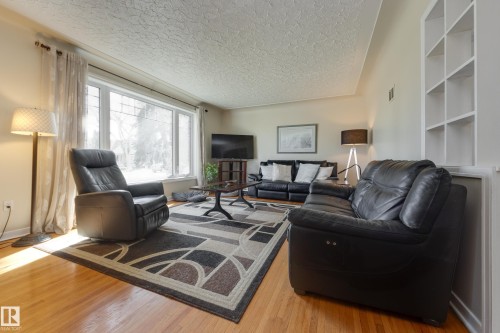 Living room featuring wood-finish flooring, a large picture window, and built-in shelving - 11516 72 Avenue, Edmonton, AB - Indoor Photo Showing Living Room