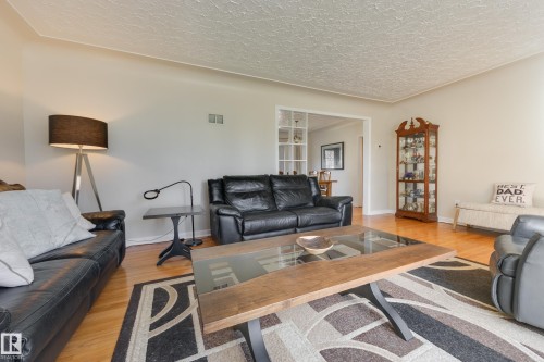 Living area featuring wood-finish flooring, a neutral color palette, and an open doorway to an adjacent room - 11516 72 Avenue, Edmonton, AB - Indoor Photo Showing Living Room