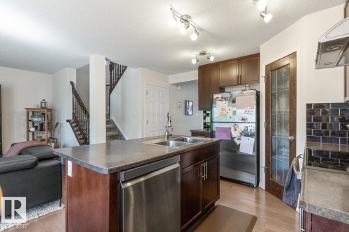 Kitchen island featuring a double-basin sink and integrated stainless steel dishwasher - 7641 Schmid Crescent, Edmonton, AB - Indoor Photo Showing Kitchen With Double Sink