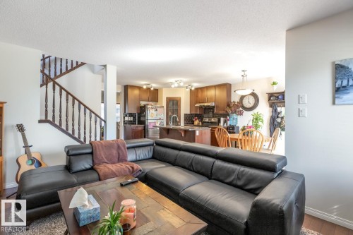 Bright living area featuring wood-finish flooring and a staircase with dark wood banisters - 7641 Schmid Crescent, Edmonton, AB - Indoor Photo Showing Living Room