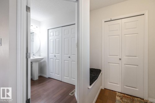 Pedestal sink with an oval mirror, overhead light fixture, and wood-finish flooring - 7641 Schmid Crescent, Edmonton, AB - Indoor Photo Showing Other Room