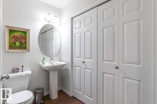 Bathroom featuring a pedestal sink with chrome faucet, an oval mirror, and a two-door closet with paneling - 7641 Schmid Crescent, Edmonton, AB - Indoor Photo Showing Bathroom