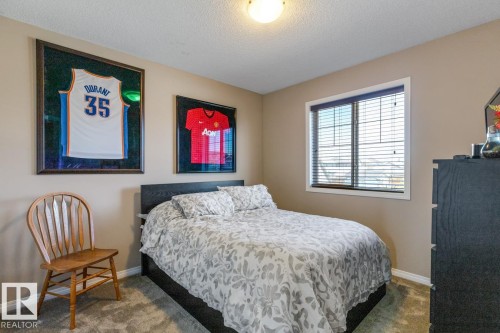Carpeted bedroom featuring a single window with blinds, beige wall paint, and a built-in ceiling light fixture - 7641 Schmid Crescent, Edmonton, AB - Indoor Photo Showing Bedroom
