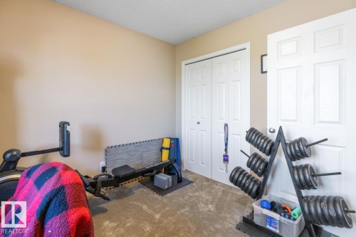 Neutral wall paint, textured carpeting, and white bi-fold closet doors - 7641 Schmid Crescent, Edmonton, AB - Indoor Photo Showing Bedroom