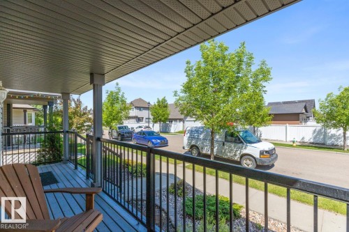 Covered front porch featuring a textured ceiling, black metal railings, and a light-toned wood-finish deck - 7641 Schmid Crescent, Edmonton, AB - Outdoor With Deck Patio Veranda With Exterior