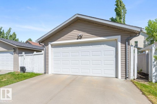 Attached garage featuring a panel-style door, exterior siding, and a concrete driveway - 7641 Schmid Crescent, Edmonton, AB - Outdoor