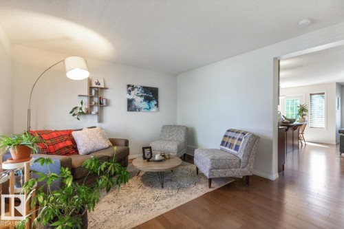 Living area featuring light-colored walls, wood-finish flooring, and an arching floor lamp - 7641 Schmid Crescent, Edmonton, AB - Indoor Photo Showing Living Room