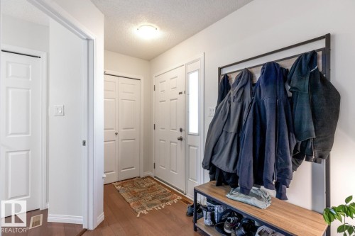 Entryway featuring wood-finish flooring, a white paneled door with a frosted glass insert, and a flush-mount ceiling light - 7641 Schmid Crescent, Edmonton, AB - Indoor
