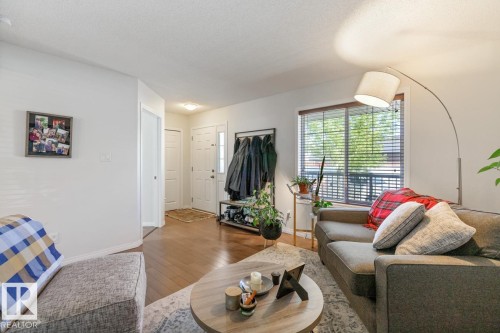 Living area featuring wood-finish flooring, white walls, and a front entry door with a sidelight - 7641 Schmid Crescent, Edmonton, AB - Indoor Photo Showing Living Room