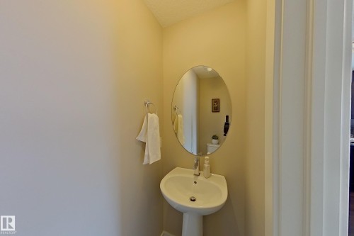 Pedestal sink with chrome faucet, complemented by an oval mirror and a chrome towel ring - 295 401 Southfork, Leduc, AB - Indoor Photo Showing Bathroom