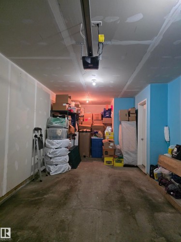 Garage space with exposed drywall, concrete flooring, and ceiling-mounted lighting fixtures - 295 401 Southfork, Leduc, AB - Indoor Photo Showing Garage