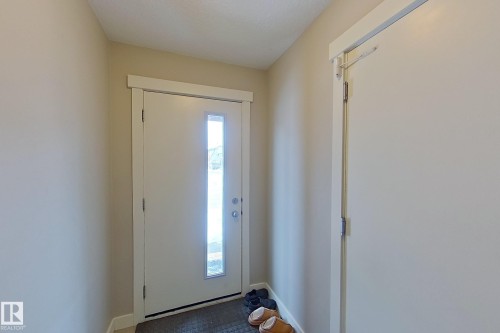 Entryway featuring a white door with vertical glass paneling, neutral wall tones, and a dark floor mat - 295 401 Southfork, Leduc, AB - Indoor Photo Showing Other Room