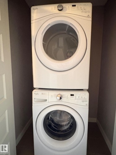 Stackable white washer and dryer units in a dedicated laundry alcove - 295 401 Southfork, Leduc, AB - Indoor Photo Showing Laundry Room
