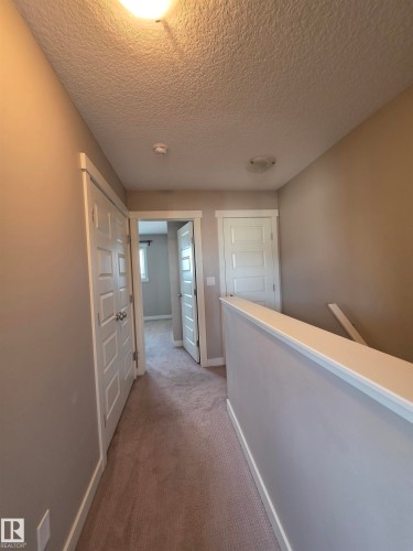 Carpeted hallway with neutral wall paint and white trim details - 295 401 Southfork, Leduc, AB - Indoor Photo Showing Other Room