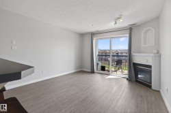 Living area featuring wood-finish flooring, a corner fireplace with white mantel, and a sliding glass door opening to an outdoor balcony - 