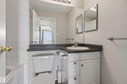 Bathroom featuring a white vanity with cabinet storage, dark countertop, and integrated sink - 
