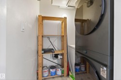 Laundry closet with stacked appliances and adjacent wood shelving unit - 