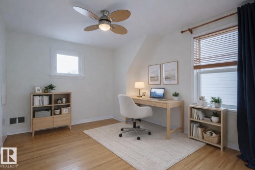 Bright room featuring a ceiling fan with integrated lighting, wood-finish flooring, and white painted walls - 11507 72 Avenue, Edmonton, AB - Indoor Photo Showing Office