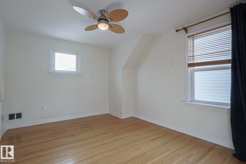 Room featuring wood-finish flooring, two windows with white trim, a ceiling fan with light fixture, and white painted walls - 11507 72 Avenue, Edmonton, AB - Indoor Photo Showing Other Room