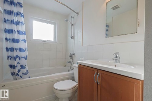 Bathroom featuring a built-in tub with a shower fixture, a window above the tub, a toilet, and a vanity with a white basin and chrome faucet - 11507 72 Avenue, Edmonton, AB - Indoor Photo Showing Bathroom