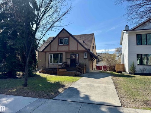 Tudor Revival architecture featuring a stucco and timber frame exterior, a prominent front gable, a concrete driveway, a sidewalk, and mature landscaping - 11507 72 Avenue, Edmonton, AB - Outdoor With Facade