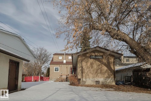 Rear exterior featuring a stucco finish, multi-level deck, and mature trees - 11507 72 Avenue, Edmonton, AB - Outdoor