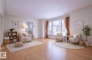 Expansive living area featuring light wood-finish flooring, a large bay window, and light-toned wall finishes - 11507 72 Avenue, Edmonton, AB  - Indoor Photo Showing Living Room 