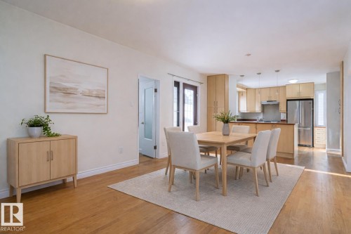 Hardwood flooring extending throughout, leading to a modern kitchen with stainless steel appliances and light wood cabinetry - 11507 72 Avenue, Edmonton, AB - Indoor Photo Showing Dining Room