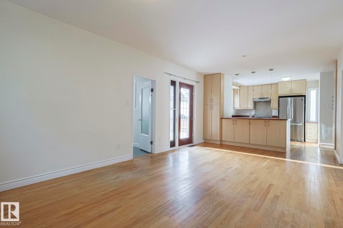 Open-concept living area featuring wood-finish flooring, a kitchen with light-toned cabinetry, stainless steel appliances, and a double-door exterior entry - 11507 72 Avenue, Edmonton, AB - Indoor Photo Showing Kitchen
