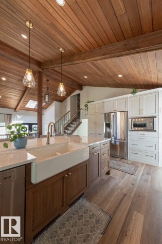 Gourmet kitchen featuring a farmhouse sink, stainless steel appliances, wood-finish flooring, a vaulted wood-paneled ceiling, and recessed lighting - 12423 28A Avenue, Edmonton, AB - Indoor Photo Showing Kitchen