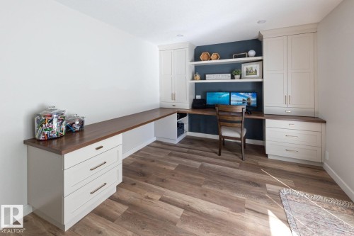 Dedicated office space featuring extensive built-in cabinetry with light-toned shaker-style doors, wood-finish countertops, and wood-finish flooring - 12423 28A Avenue, Edmonton, AB - Indoor