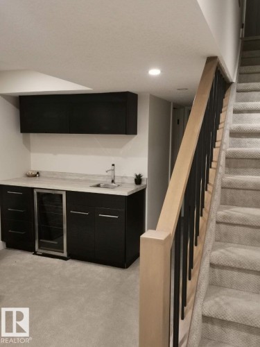 Wet bar featuring dark cabinetry, an undermount sink, and a built-in beverage refrigerator - 12423 28A Avenue, Edmonton, AB - Indoor Photo Showing Other Room