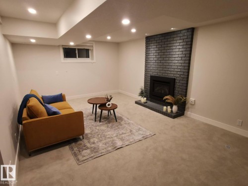 Recessed lighting illuminates the carpeted room, featuring a dark brick fireplace with a hearth - 12423 28A Avenue, Edmonton, AB - Indoor With Fireplace