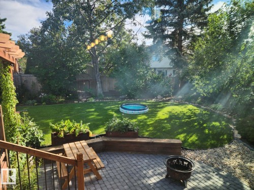 Expansive backyard featuring a paver patio, wood deck with pergola, raised garden beds, a manicured lawn, and mature trees - 12423 28A Avenue, Edmonton, AB - Outdoor
