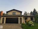 Stucco exterior residence featuring a prominent black garage door, stone veneer accents, and a contrasting dark roof - 12423 28A Avenue, Edmonton, AB  - Outdoor 