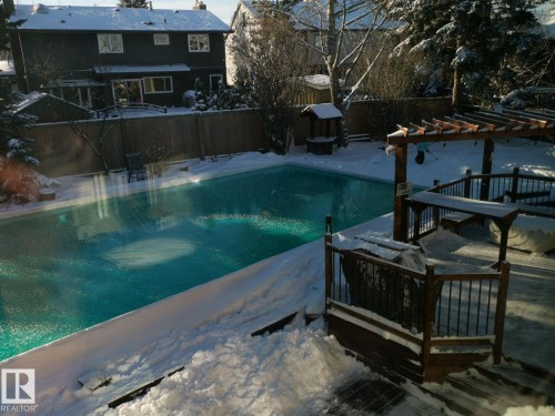 Backyard featuring a swimming pool, wooden decking, pergola structure, and privacy fencing - 12423 28A Avenue, Edmonton, AB - Outdoor With In Ground Pool