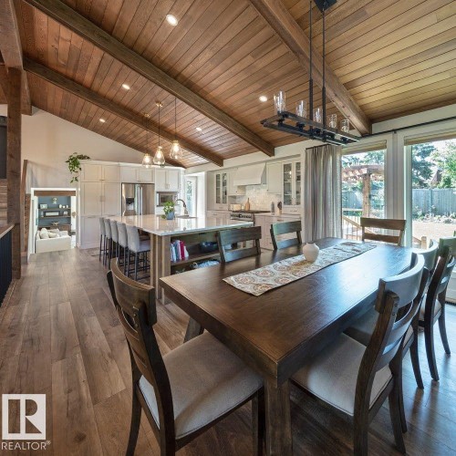 Open-concept living area featuring a vaulted wood-paneled ceiling with exposed beams, wood-finish flooring, a spacious kitchen island with seating, pendant lighting, and abundant natural light from large windows - 12423 28A Avenue, Edmonton, AB - Indoor Photo Showing Dining Room