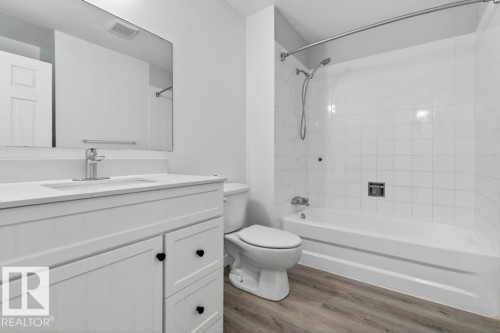 Bathroom featuring a white vanity with black hardware, a rectangular vanity mirror, and wood-finish flooring - 3E Twin Terrace, Edmonton, AB - Indoor Photo Showing Bathroom
