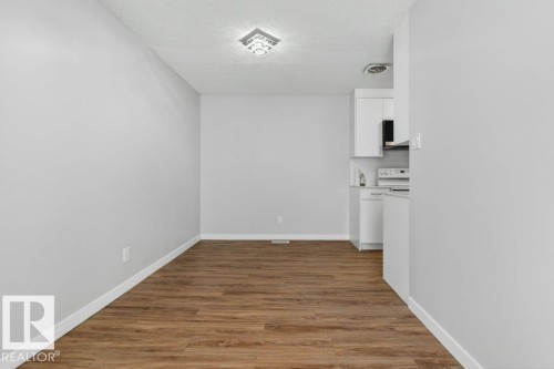 Kitchen with white cabinetry, black appliances, and wood-finish flooring - 3E Twin Terrace, Edmonton, AB - Indoor Photo Showing Other Room