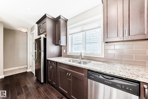 Kitchen featuring dark wood-finish cabinetry, light speckled countertops, and a subway tile backsplash - 10519 114 Avenue, Edmonton, AB - Indoor Photo Showing Kitchen With Double Sink