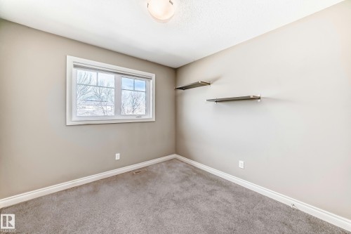 Neutral-toned room featuring a large window, light-colored walls, ceiling-mounted lighting, and built-in wall shelves - 10519 114 Avenue, Edmonton, AB - Indoor Photo Showing Other Room