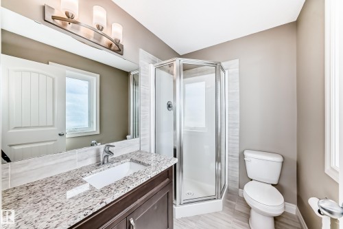Bathroom featuring a corner shower with glass enclosure, single vanity with granite countertop, integrated sink, and chrome faucet - 10519 114 Avenue, Edmonton, AB - Indoor Photo Showing Bathroom