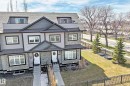 Modern townhome featuring gray siding, stone accents, black trim windows, and a dark shingle roof - 10519 114 Avenue, Edmonton, AB  - Outdoor 