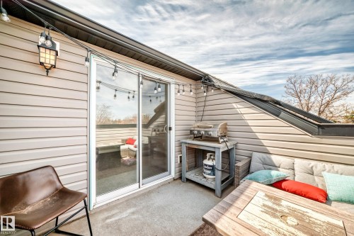 Exterior patio featuring a sliding glass door, light-toned siding, and a prominent wall-mounted light fixture - 10519 114 Avenue, Edmonton, AB - Outdoor With Exterior