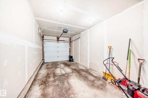 Single-car garage with unfinished drywall, concrete flooring, and an automatic overhead door - 10519 114 Avenue, Edmonton, AB - Indoor Photo Showing Garage