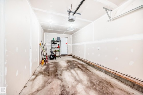 Garage space featuring unfinished drywall, concrete flooring, and a garage door opener system - 10519 114 Avenue, Edmonton, AB - Indoor Photo Showing Garage